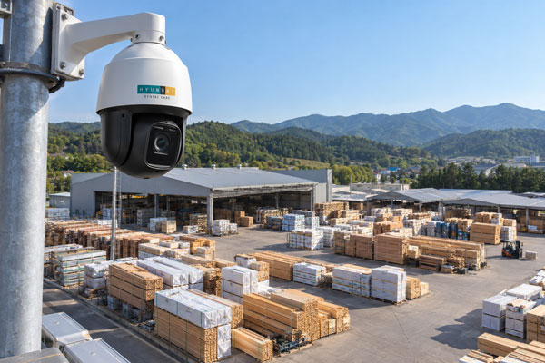 목재와 건축 자재가 적재된 넓은 야적장을 내려다보도록 설치된 현대렌탈케어 PTZ CCTV 예시